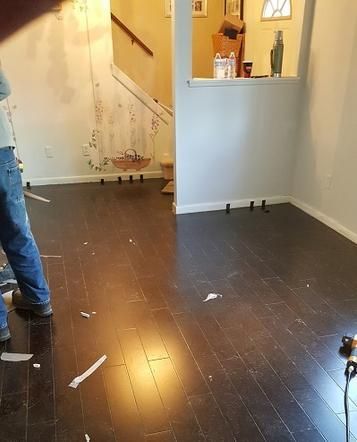 A man is standing in a room with a wooden floor.