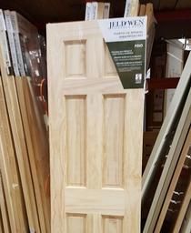 A wooden door is sitting on top of a pile of wood in a warehouse.