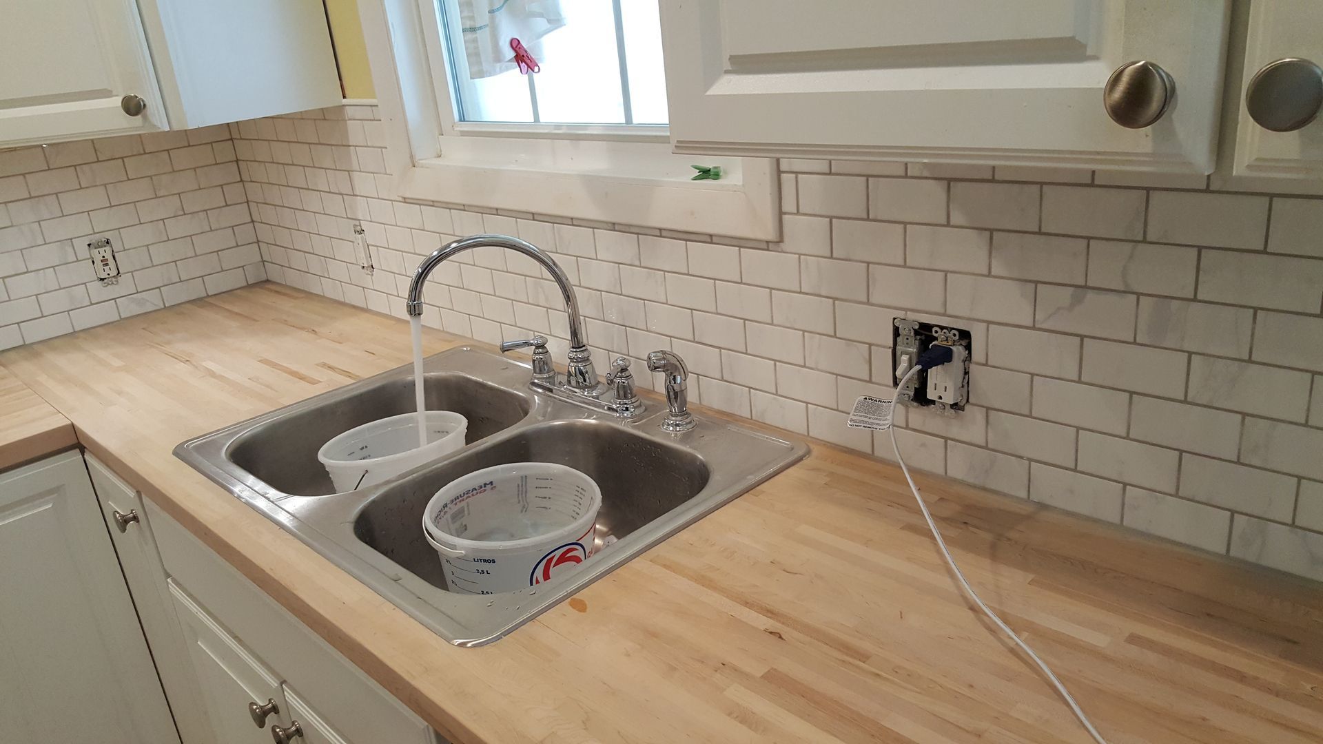 A kitchen sink with two buckets in it and a faucet.