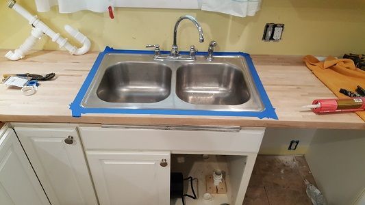 A kitchen sink is taped to the counter with blue tape.
