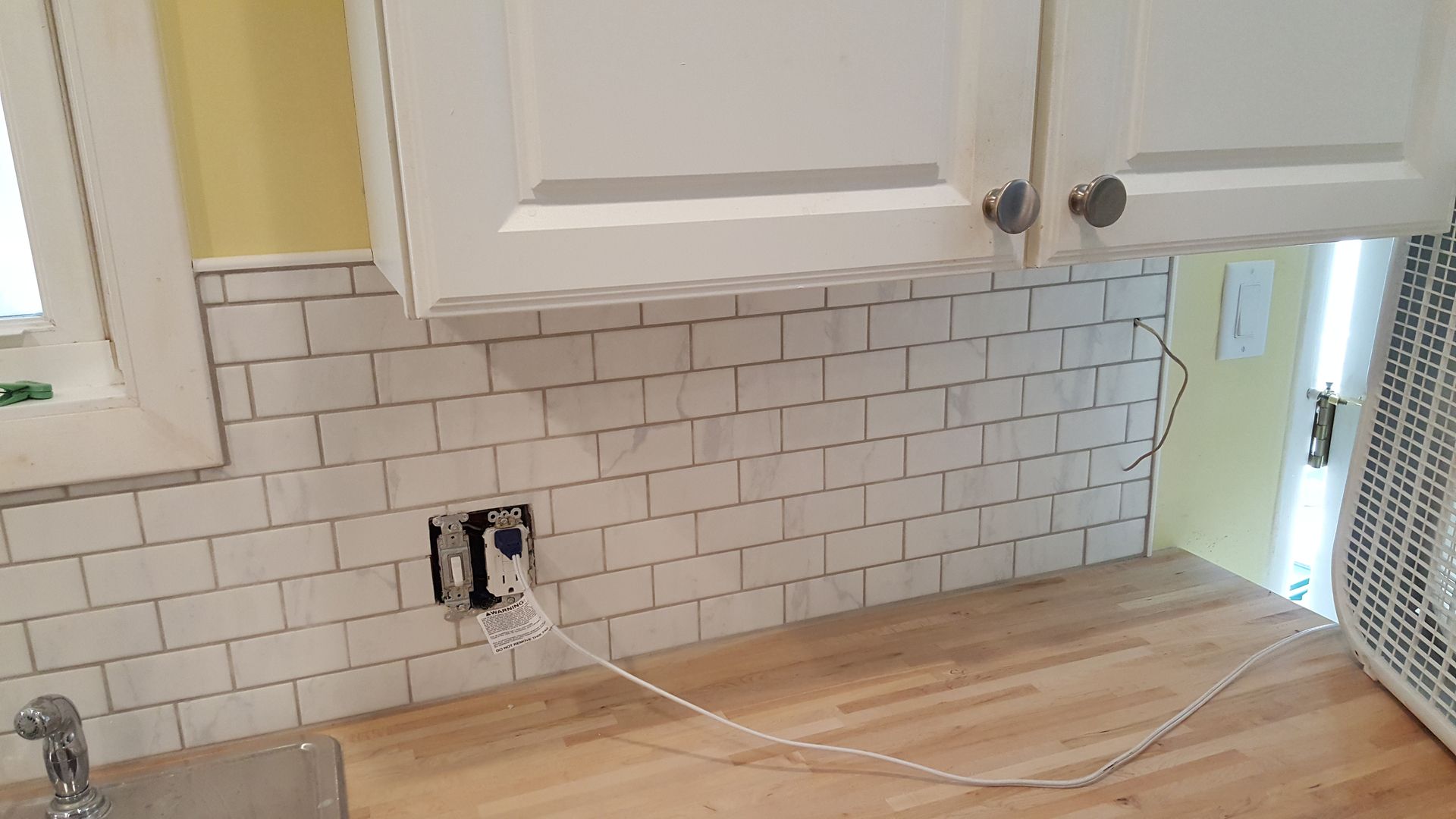 A kitchen with white cabinets and a wooden counter top.