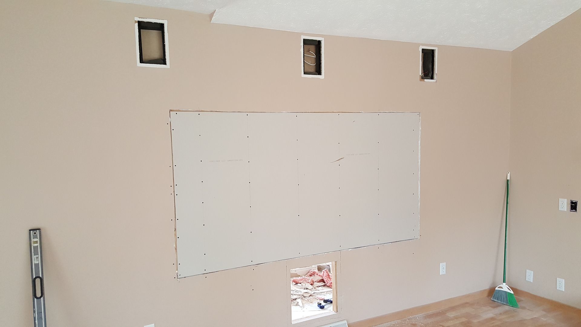 A room with a white board on the wall and a broom.