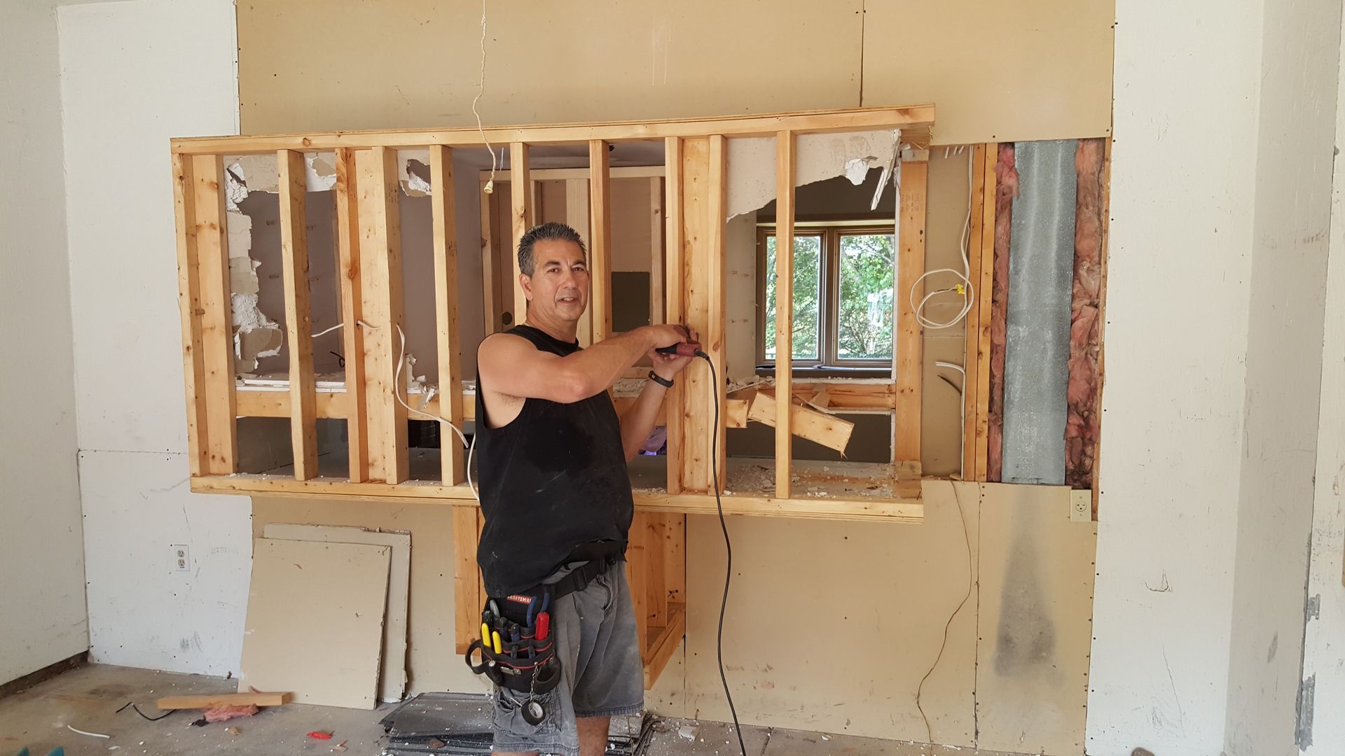 A man is standing in a room with a hole in the wall.
