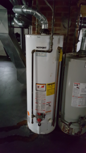 Two water heaters are sitting next to each other in a basement.