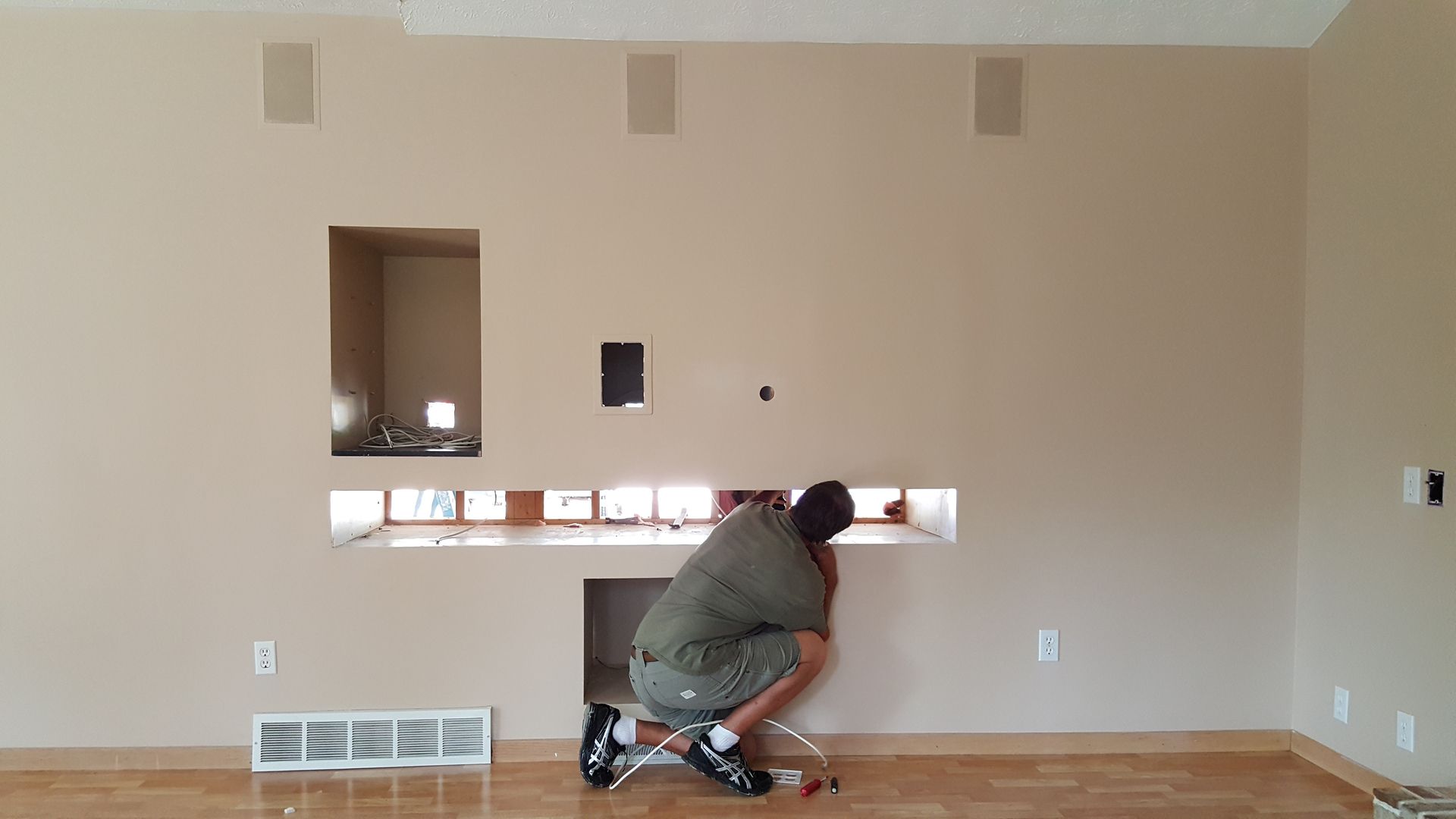 A man is working on a fireplace in a living room.