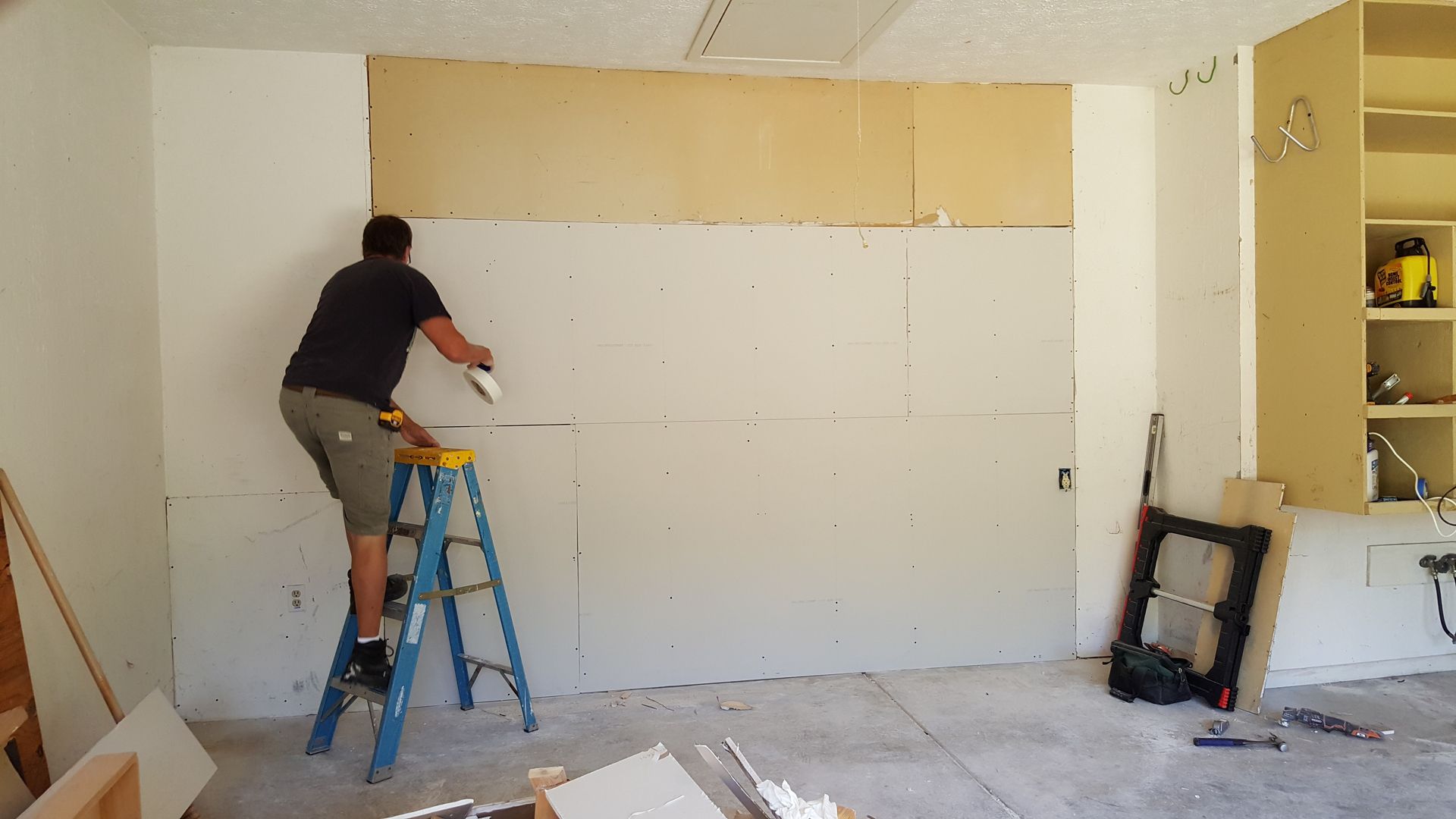 A man on a ladder is working on a wall