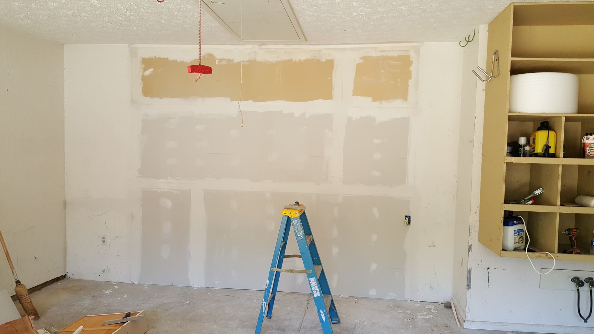 A blue ladder is sitting in a room next to a wall.