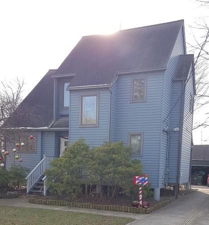 A large blue house with a black roof is for sale.