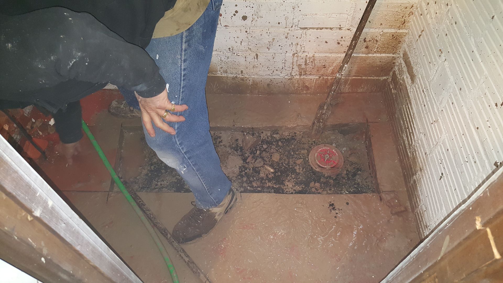 A person is standing in a dirty room with a broom.