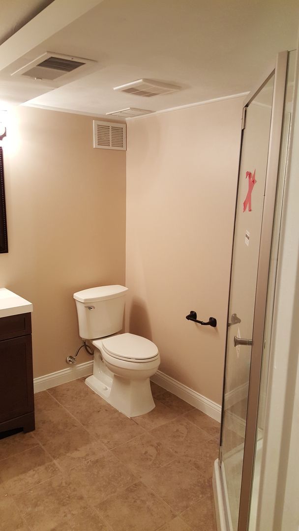 A bathroom with a toilet , sink and shower.