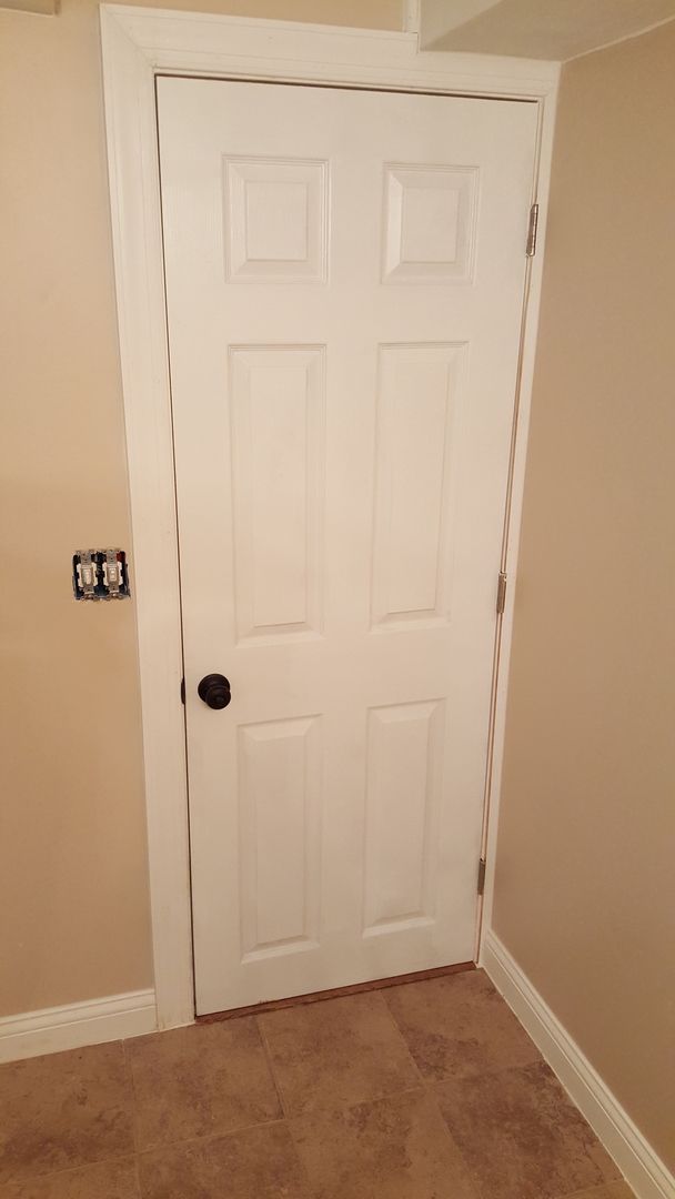 A white door with a black handle is in a room.