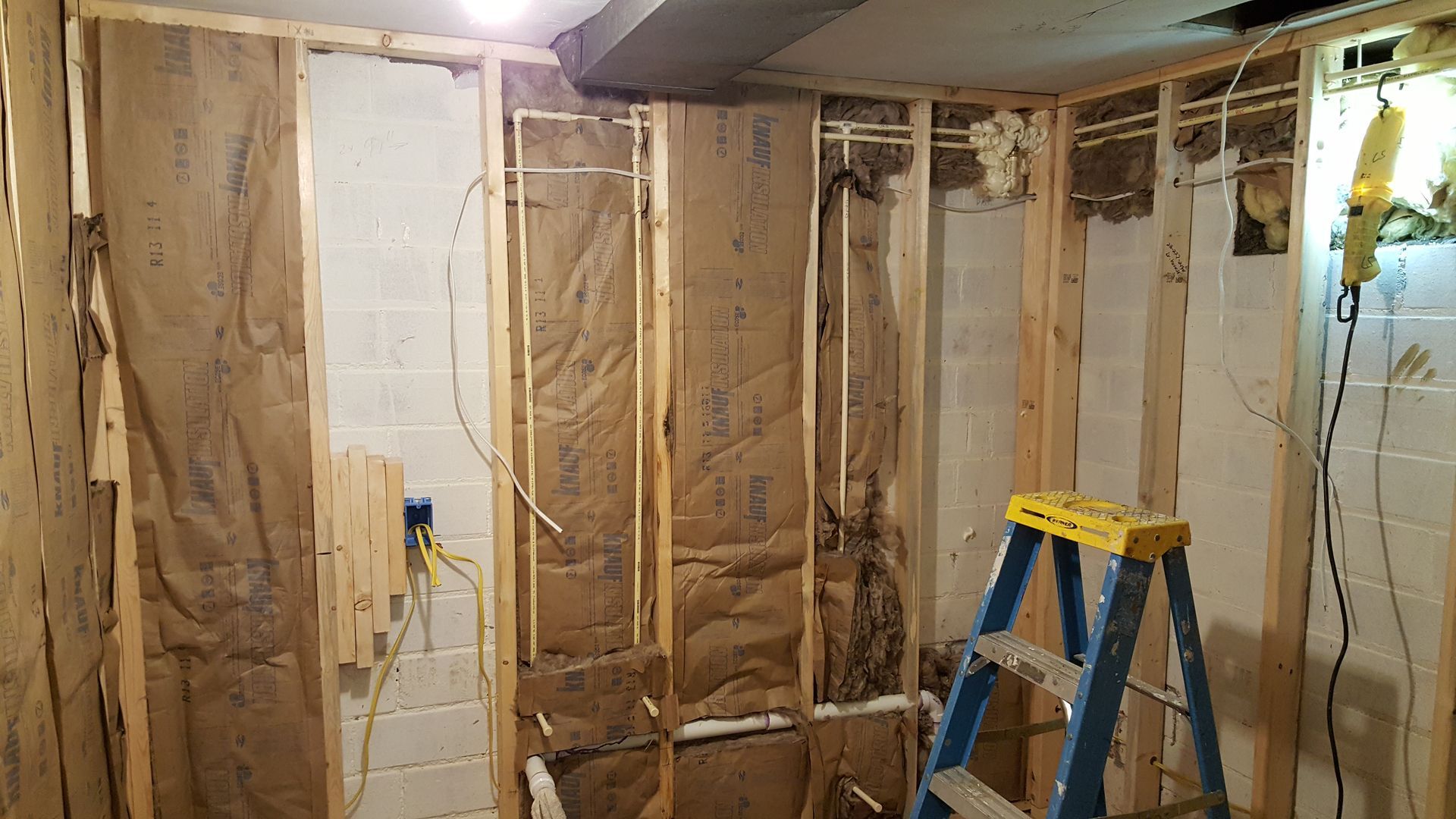 A blue ladder is sitting in a room under construction.