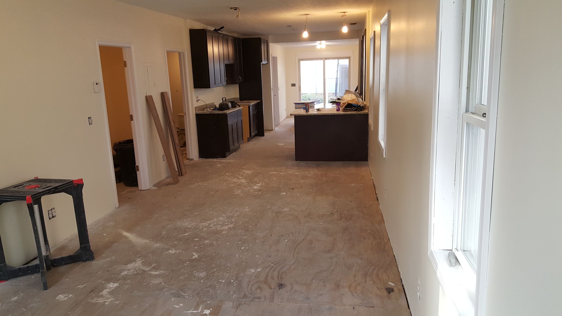 A long hallway leading to a kitchen in a house under construction.