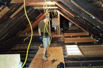 A man is standing on a wooden floor in an attic.