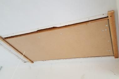 A wooden ladder is hanging from the ceiling of a room.