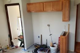 A man is working in a laundry room with wooden cabinets.
