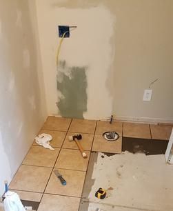 A bathroom with tile floors and a hammer on the floor.