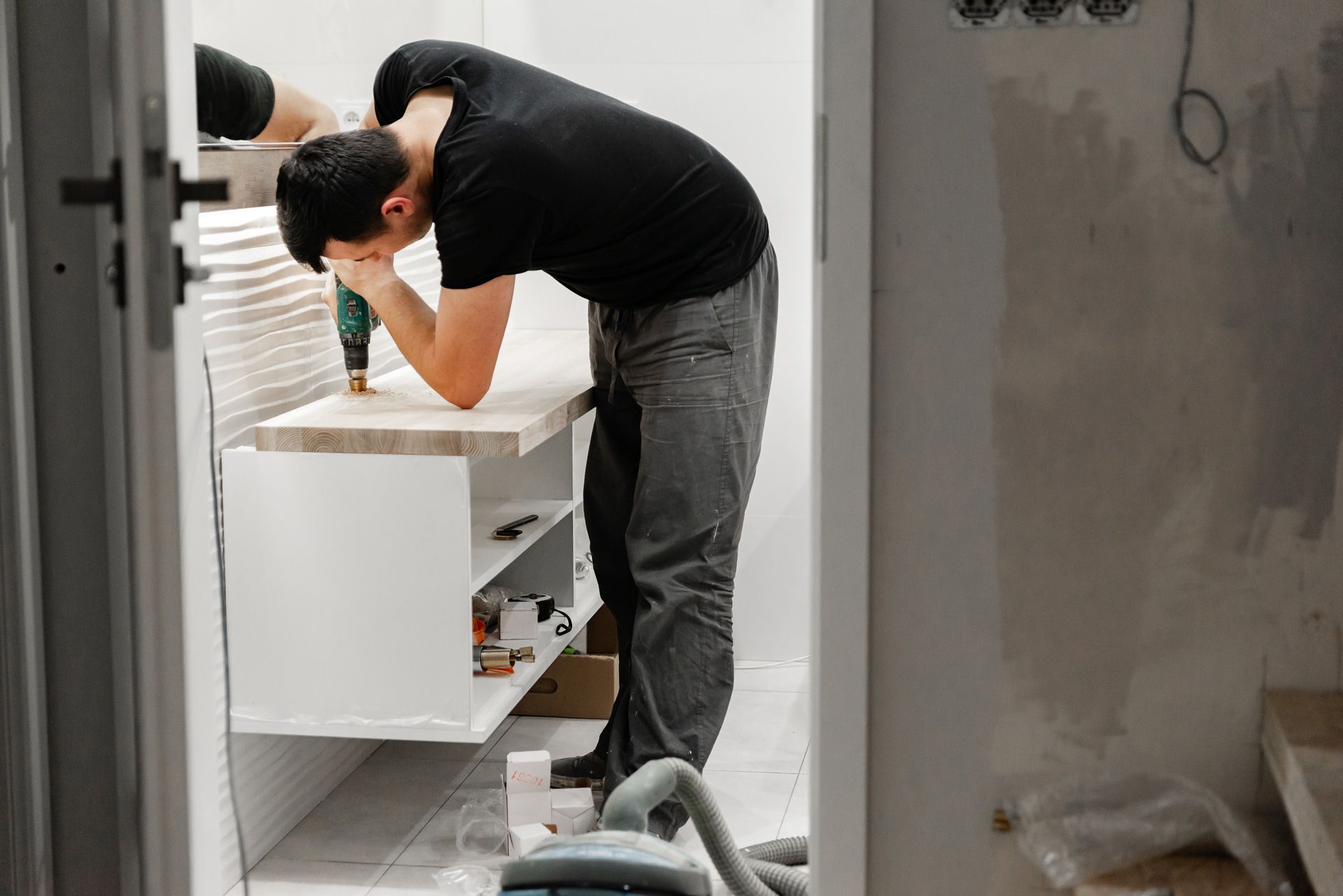 A man is using a drill to install a bathroom vanity.