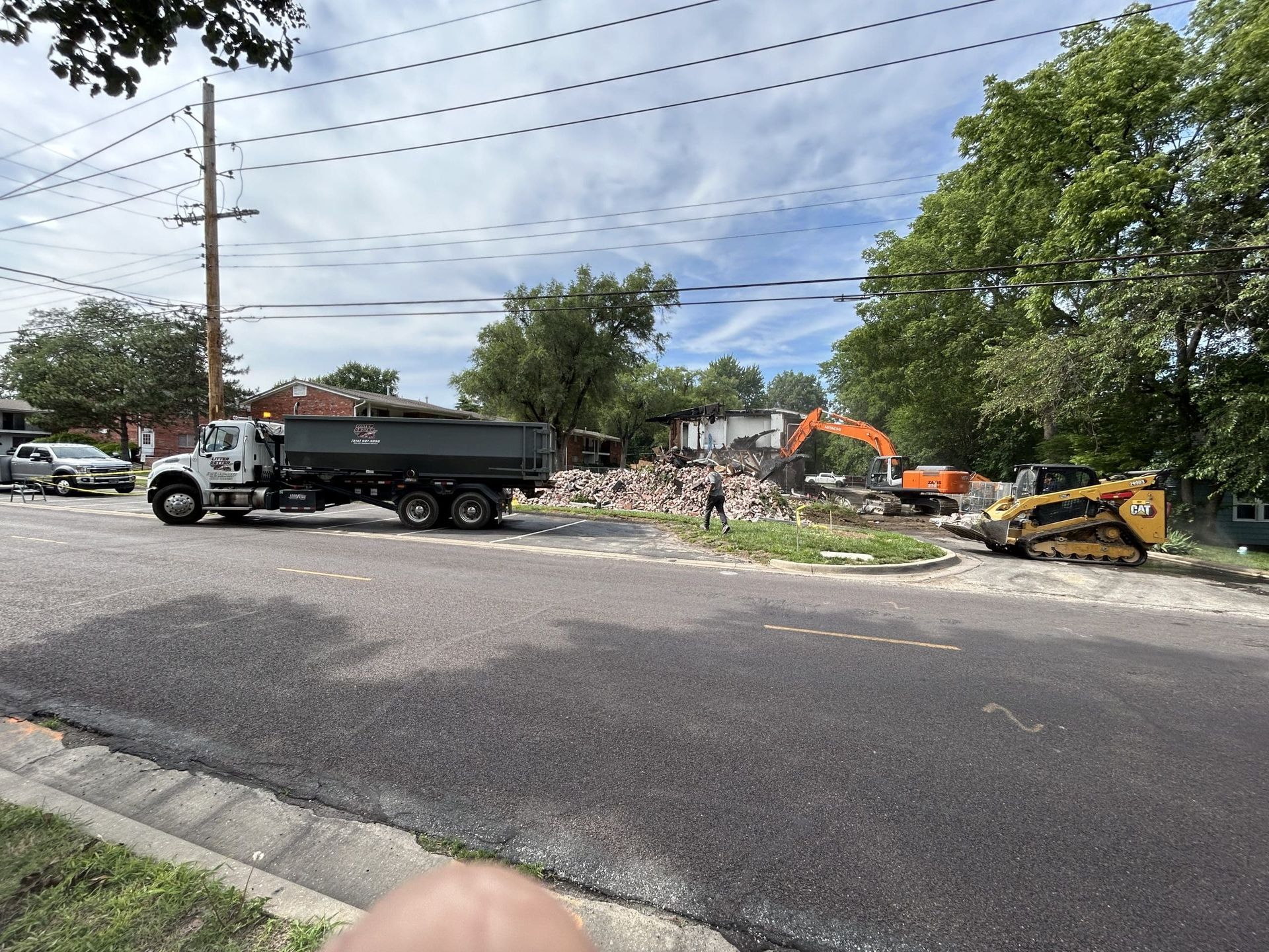 A dump truck is driving down a street next to a construction site.