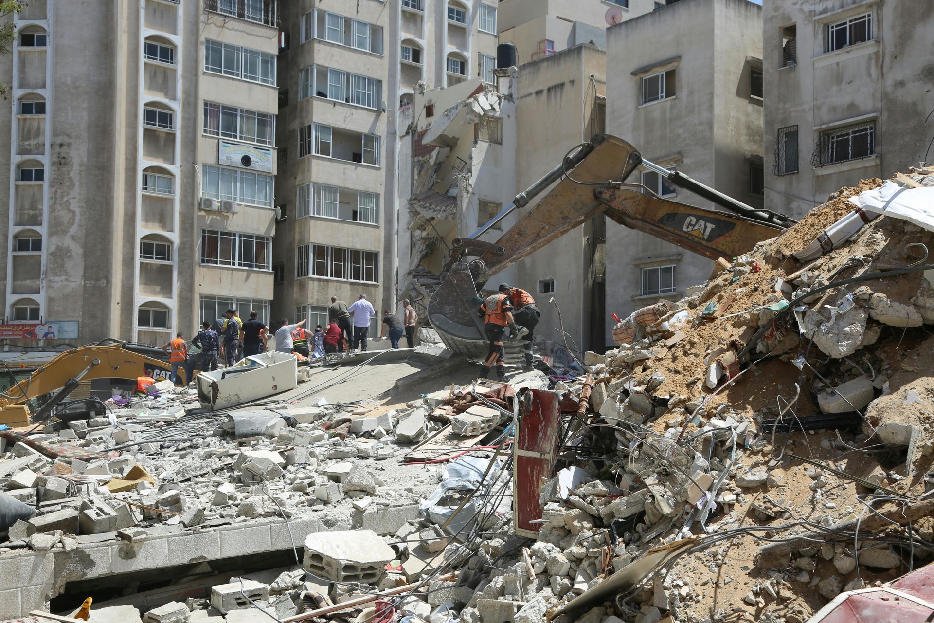 A group of people are standing in front of a pile of rubble.