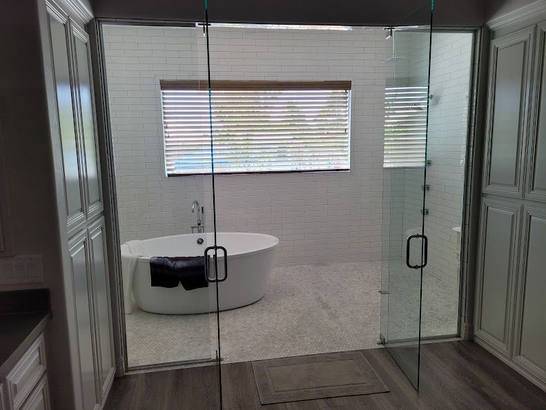Modern bathroom with a freestanding tub, glass shower, and white cabinets.