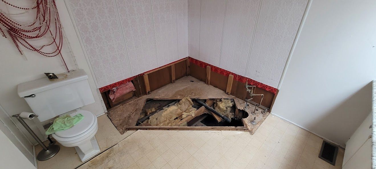 Bathroom with exposed floorboards, walls, and a toilet. A red wire hangs.