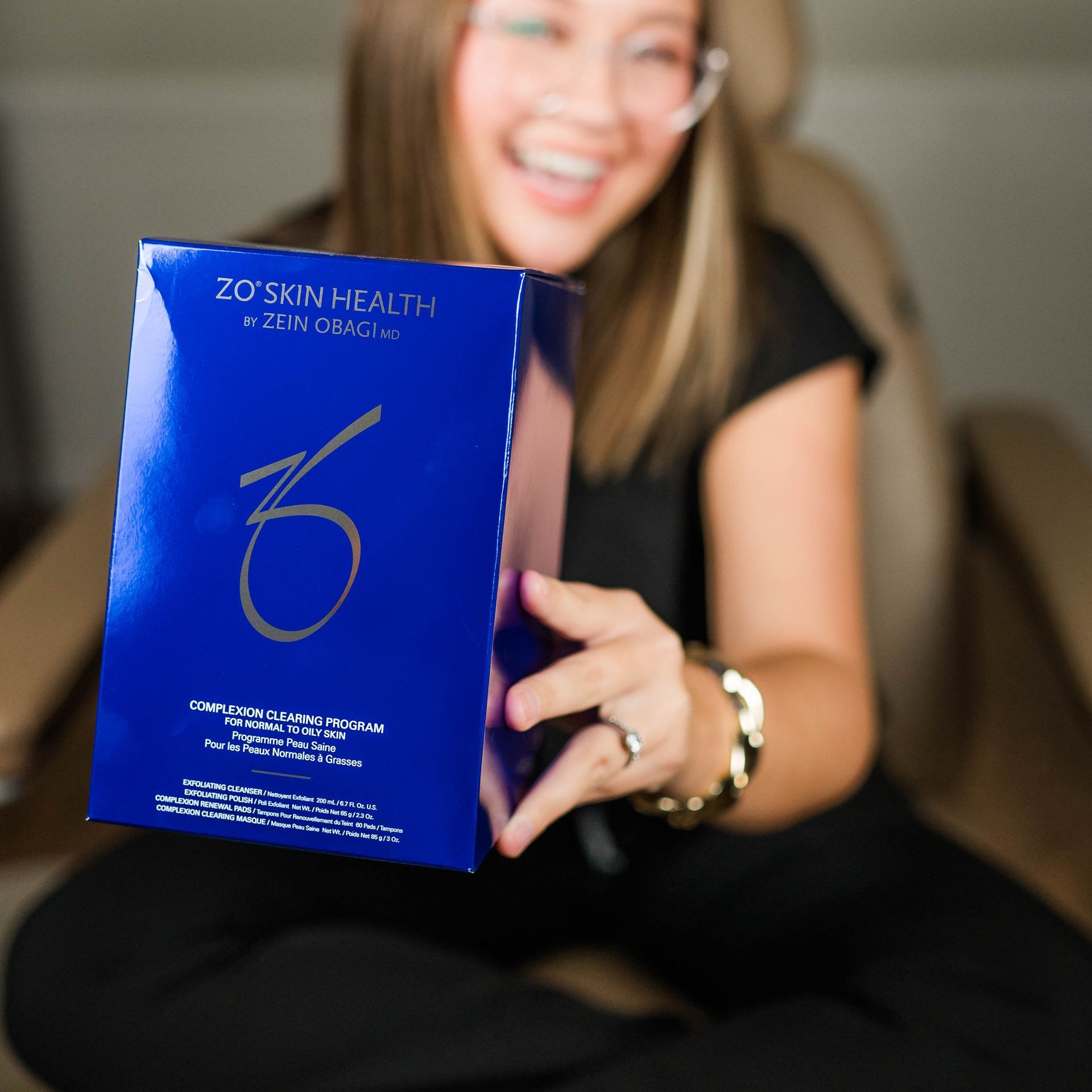 A woman is smiling and touching her face with her hands.