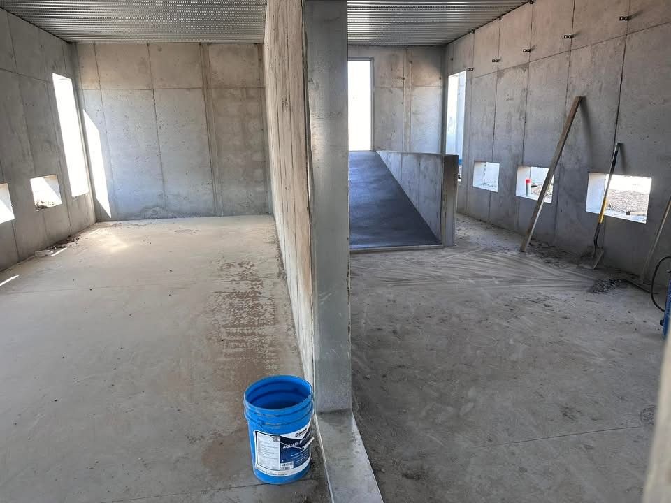 An empty room with a blue bucket on the floor
