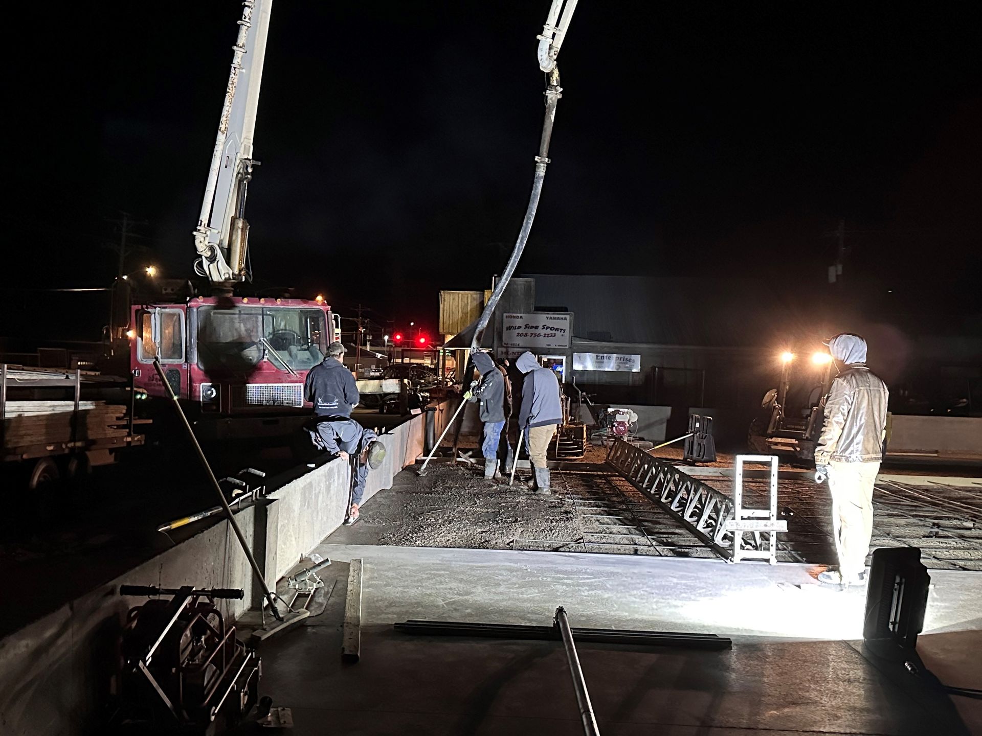 A group of construction workers are working on a bridge at night.