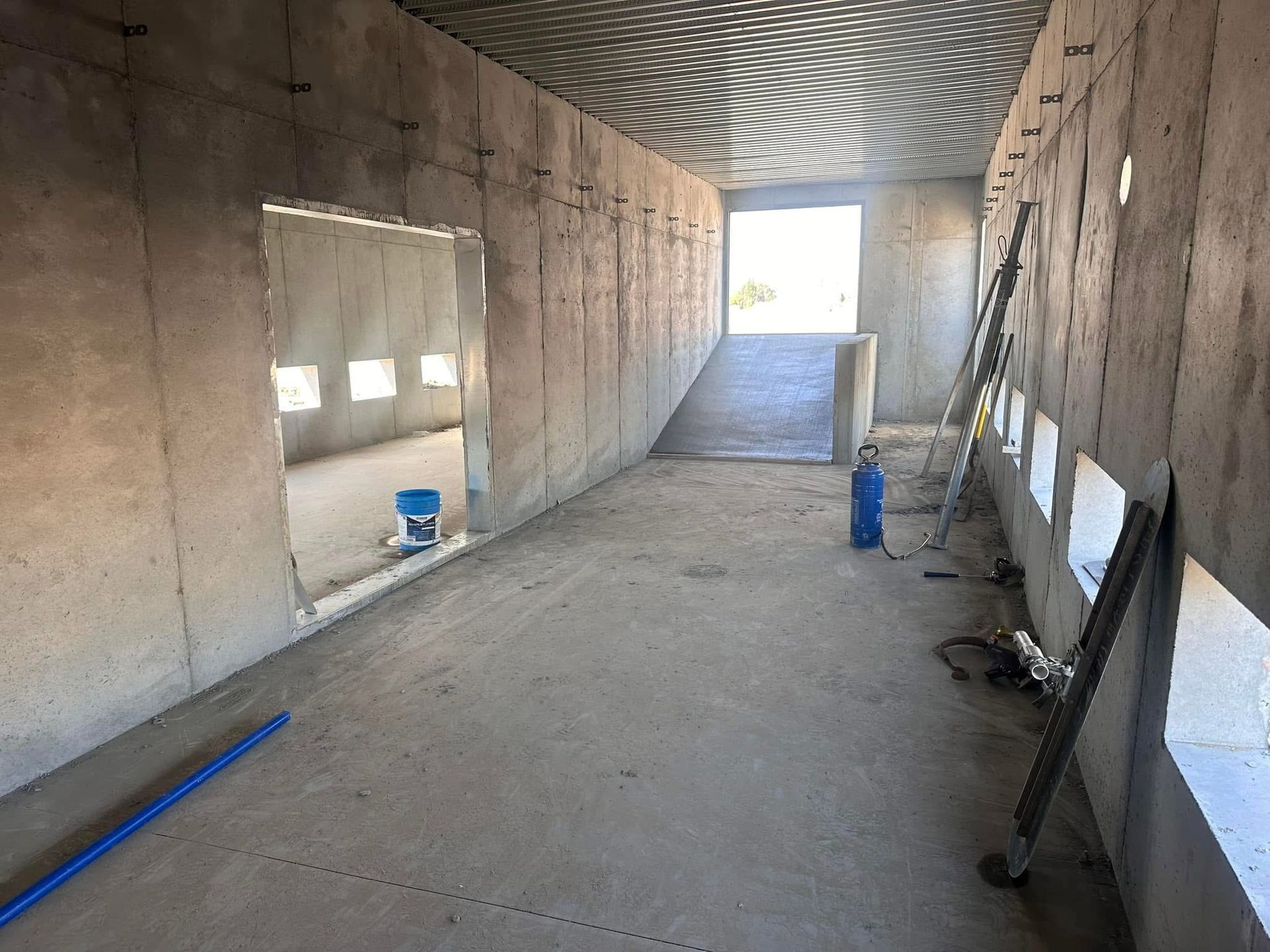 An empty room with a ladder and a blue bucket