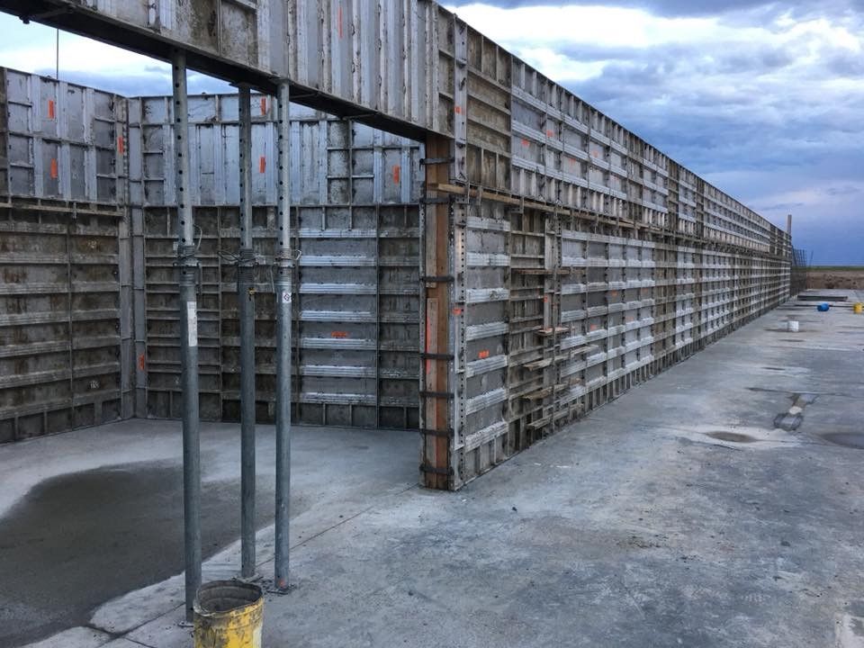 A large concrete wall is being built on a construction site.