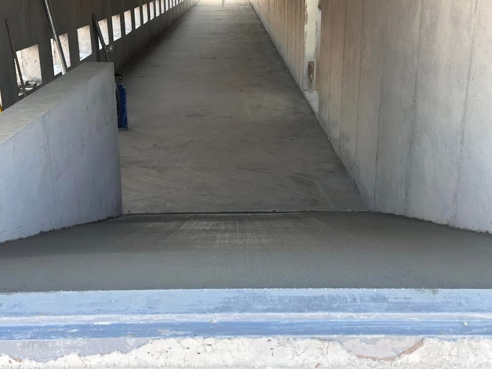 A concrete ramp leading into a tunnel under a bridge.