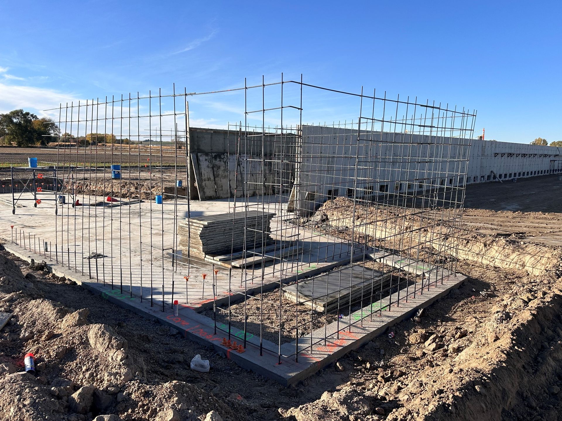 A large building is being built in the middle of a dirt field.