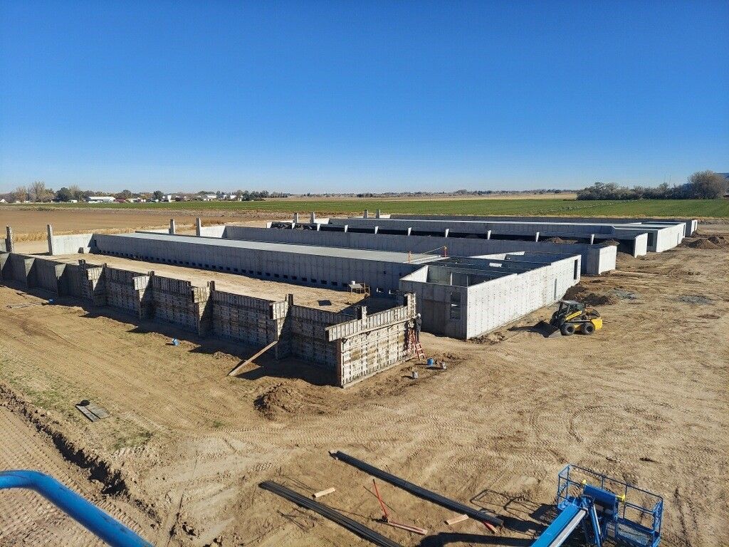 A large concrete structure is being built in a dirt field.