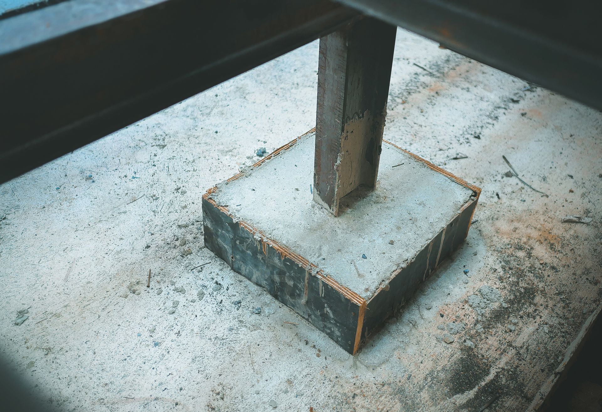 A metal post is sitting on top of a concrete base.