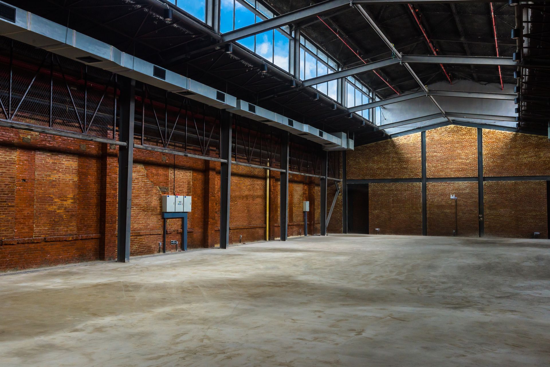 An empty warehouse with brick walls and a concrete floor.