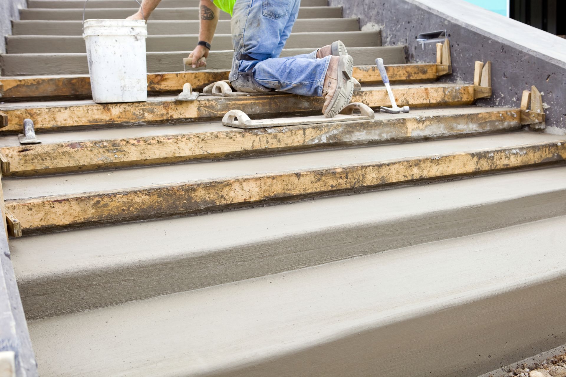A man is kneeling down on a set of concrete stairs.