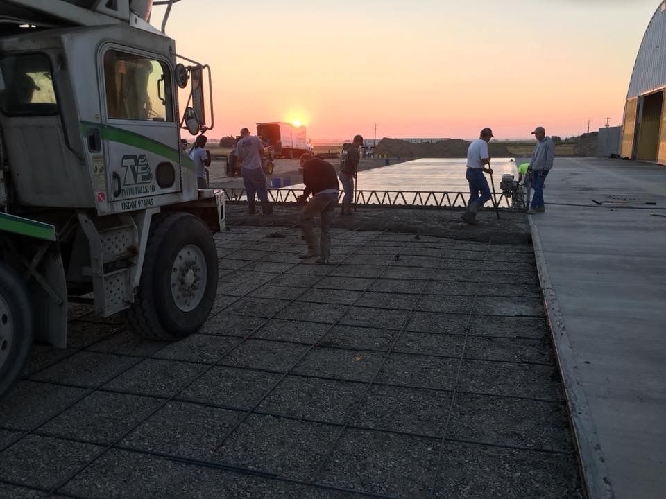 A construction worker is raking concrete on a construction site.