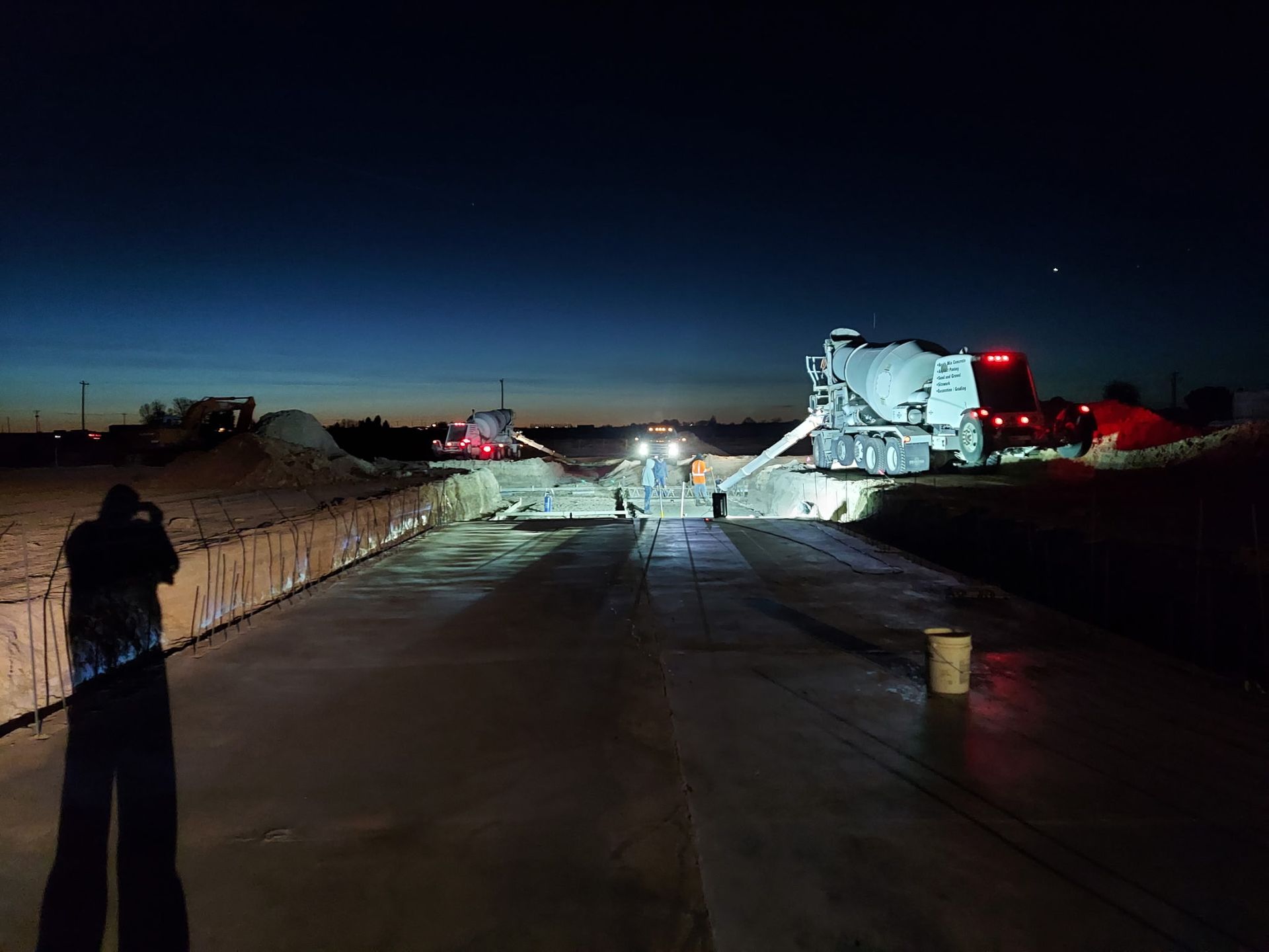A man is spreading concrete on a sidewalk with a trowel.