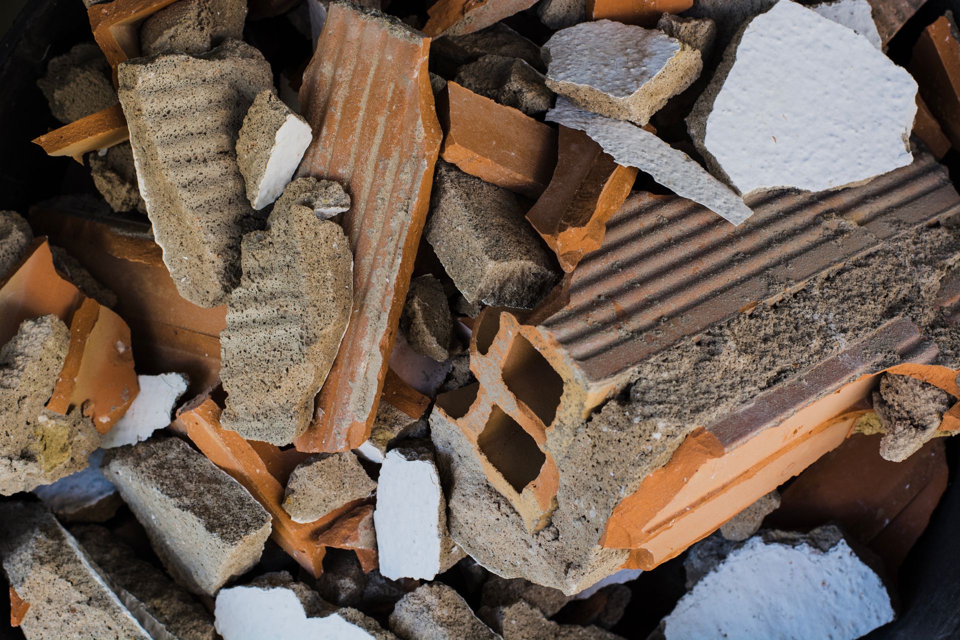 A pile of broken bricks and concrete in a black bucket.