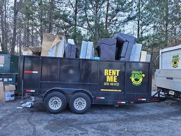 A dumpster that says rent me is filled with furniture.