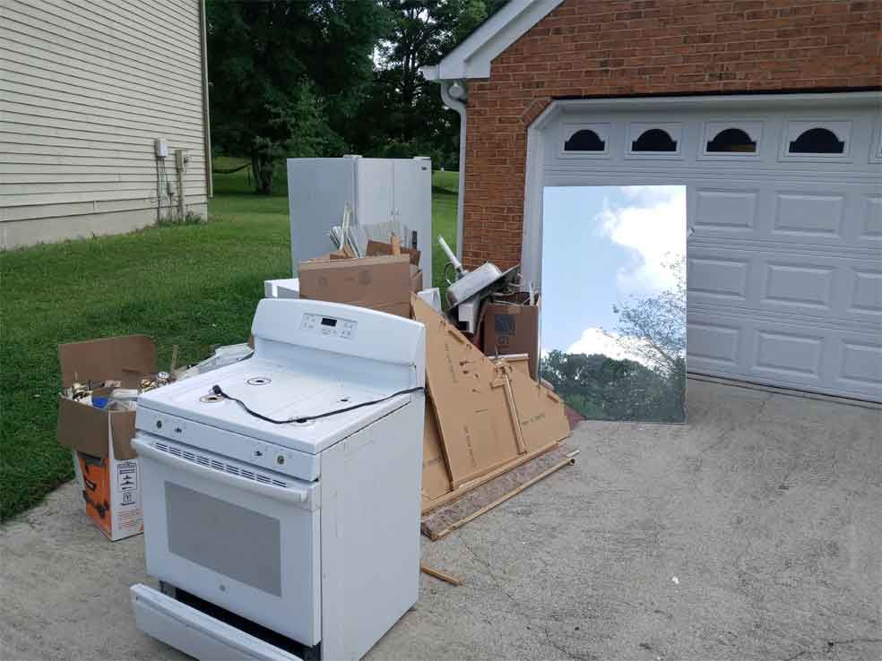 A white stove is sitting in a driveway next to a garage door.