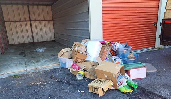 A pile of cardboard boxes is sitting on the side of the road in front of a garage.