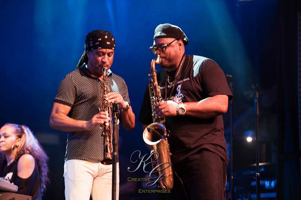 Deon Yates and Marion Meadows playing saxophones on a stage.