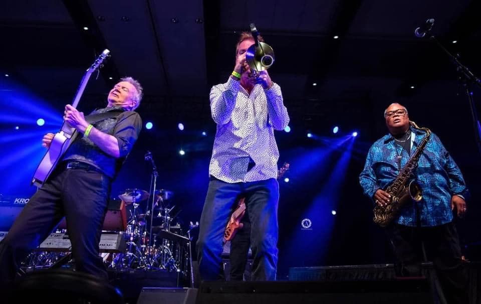 Trumpeter Rob Zinn and a group of men are playing instruments on a stage.