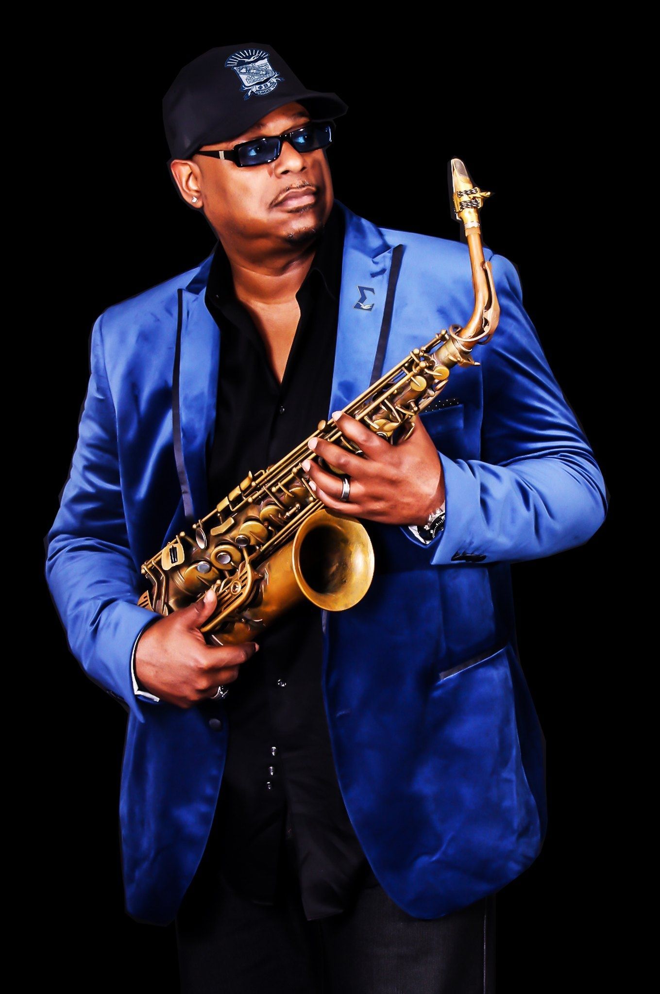Deon Yates in a blue suit is holding a saxophone