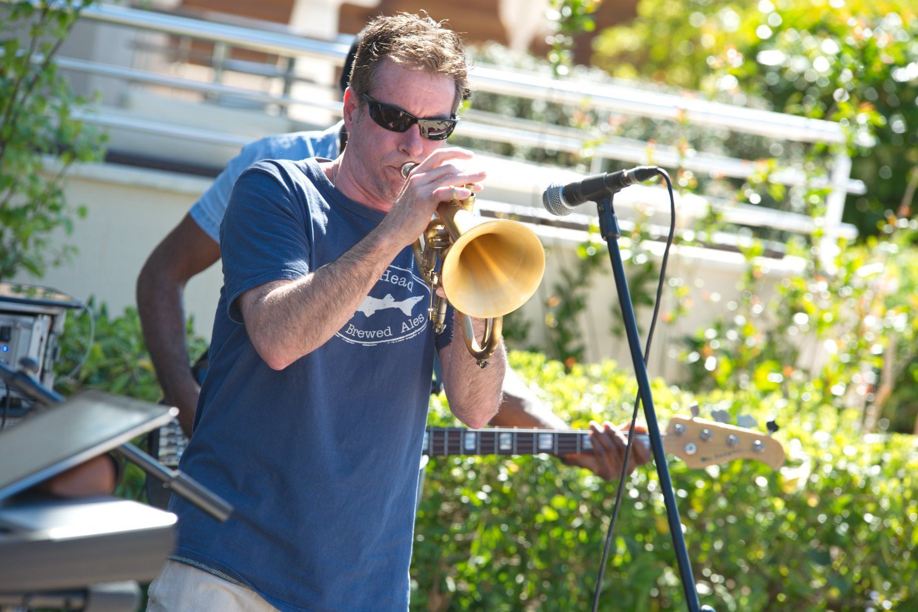 Rob Zinn in a blue shirt is playing a trumpet
