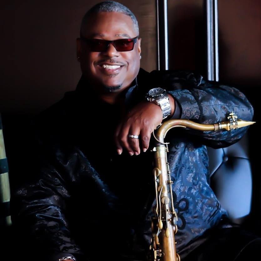 Deon Yates wearing sunglasses is leaning on a saxophone