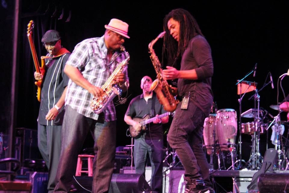 Deon Yates & Paul Taylor playing  saxophone on a stage with other musicians