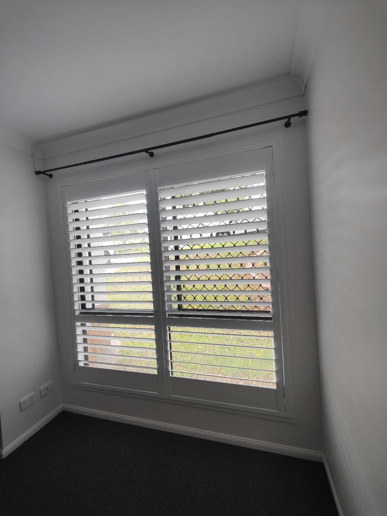 A room with a window and shutters on it.